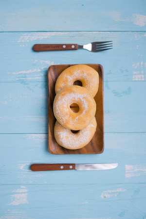 Breakfast concept: Donut on plate with fork and knife on wooden backgroundの写真素材