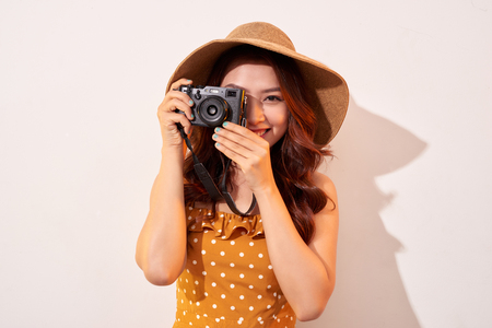 Woman traveler with a camera, beige backgroundの写真素材