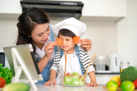Happy family in the kitchen. Mother and child daughter are preparing the vegetables and fruit.の写真素材