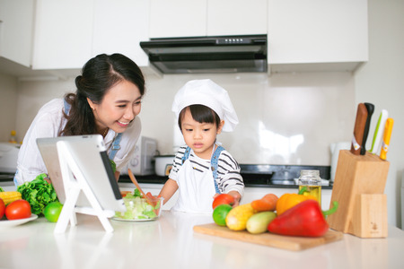 Mother with her daughter preparing lunch in the kitchen and enjoying together.の写真素材