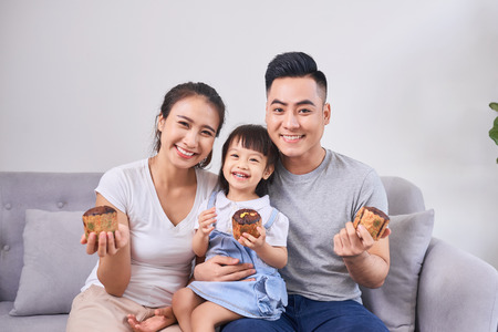 Lively family eating cupcakes in the living room at homeの写真素材