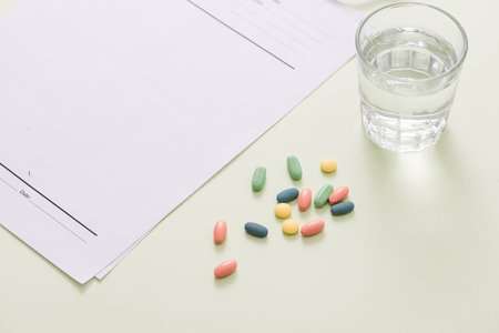 Stethoscope, pills and glass of water on light green background. medicine conceptの写真素材