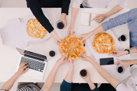 Business team is eating pizza at work while workingの写真素材