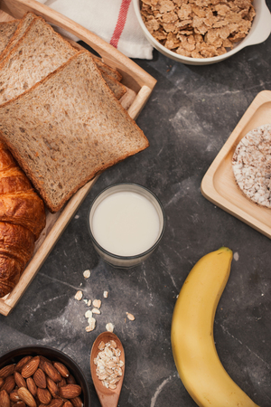 Photo of bread, bun, milk, almonds and fresh milk on table with skin color background. Breakfast preparation, daily product.の写真素材