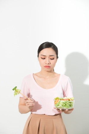 unhappy asian women is on dieting time. girl do not want to eat vegetables and dislike taste of vegetable.の写真素材