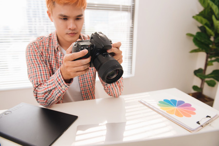 Male photographer, sitting at his desk, looking to cameraの写真素材