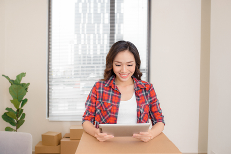 Young woman using digital tablet during moving in new apartmentの写真素材