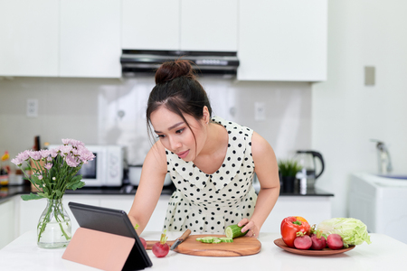 woman using tablet while making a healthy salad at the kitchenの写真素材