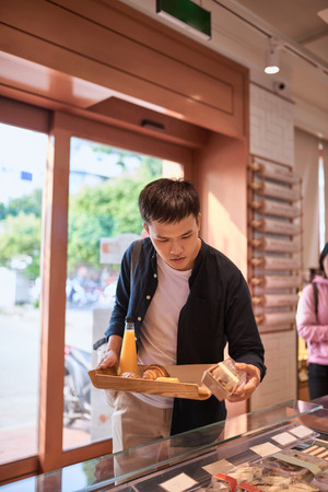 Handsome asian man buying bakery for coffee break in the afternoon. Bakery and Coffee break.の写真素材