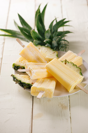 Old and rustic wooden table with homemade Pineapple Pipsicles (selective focus; close-up shot)の写真素材
