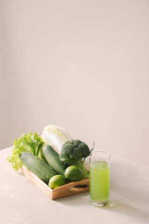 Vegan diet food. Detox drinks. Freshly squeezed juices and smoothies from vegetables. On white background, wooden tray, ingredients. Copy spaceの写真素材