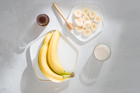 Yummy bananas and bowl with slices on wooden backgroundの写真素材