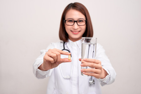 Doctor woman holding water and medicine on white background.の写真素材