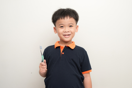 Cheerful little boy holding a tooth brush over white background, Studio portrait of a healthy mixed race boy with a toothbrush isolatedの写真素材