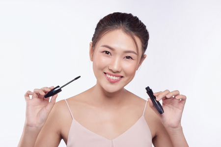 Mascara woman putting makeup on eyes. Asian female model face closeup with eye brush on eyelashes.の写真素材
