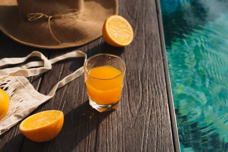 Beach hat, orange juice and sunglasses near the swimming poolの写真素材