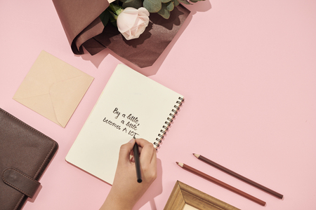 Woman's hand with pen writing on the greeting card on the table. Pink roses. Fresh flowers.の写真素材