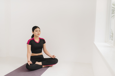 A woman practices yoga near the windowの写真素材