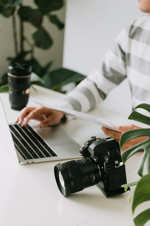 male photographer holding digital camera above the desk in his photo studioの写真素材