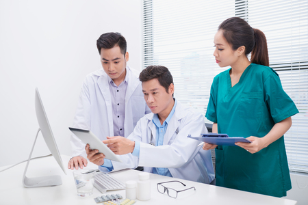Group of doctors and nurses examining medical report of patient. Team of doctors working together on patients file at hospital.の写真素材