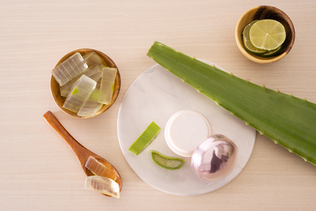 Jar of cream, peeled aloe, lemon and  aloe leave and chopped aloe on marble round boardの写真素材