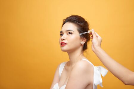 Pretty Caucasian woman putting cosmetic serum on her face at bathroomの写真素材