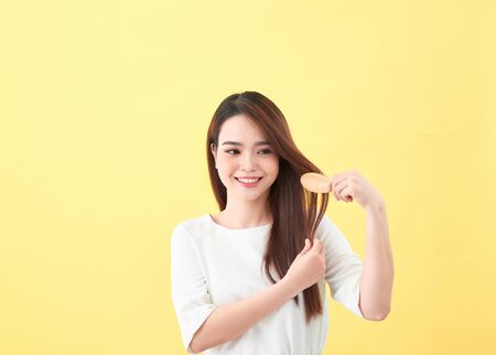 Portrait of beautiful young woman combing her hair and smilingの写真素材