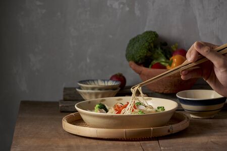 Hand uses chopsticks to pickup tasty noodles