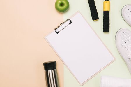 Athlete's set with female clothing, dumbbells and bottle of water on pastel color background