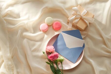 Envelope wih blank paper card on the light fabric background with lusianthus and gift box, top viewの写真素材