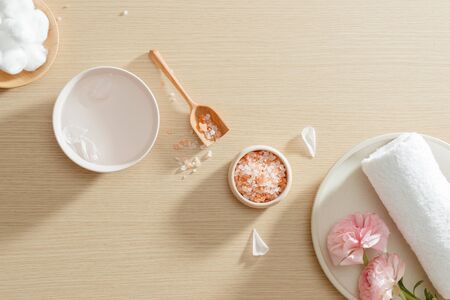 Spa setting of salt, towel, flower on plate on wood background with copy space. Relax. Close up. Top view.の写真素材