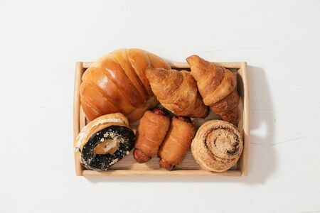 almond donut bun, croissant, crab cake, soft roll cake with sausage put on wooden plate, selective...