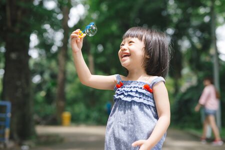 Portrait of funny lovely little girl blowing soap bubblesの写真素材