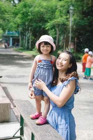 Happy family having fun with animals safari park on warm summer day.