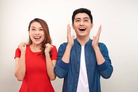 Young asian couple in love over isolated background celebrating surprised and amazed for success...