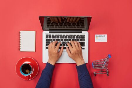 Man hand typing on laptop keyboard with blank screen monitor on red backgroundの写真素材