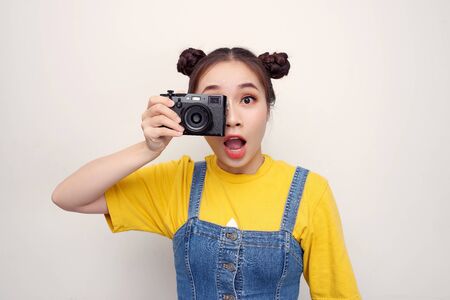 Image of excited paparazzi girl  holding retro camera at face and photographing isolated over white...
