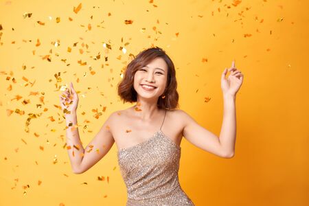 Young woman dancing under confetti during a celebrationの写真素材