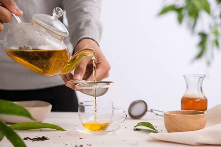 Poured from a teapot cup of tea on a wooden tableの写真素材