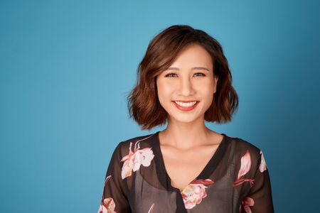 Chilling girl with short hairstyle standing in room on light blue background.の写真素材