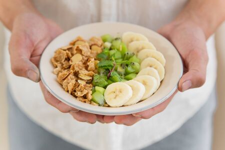 Crop man close up eating oat and fruits bowl for breakfast