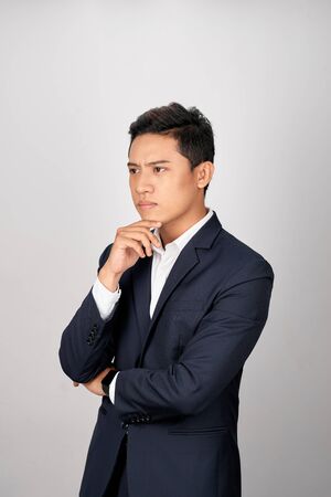 Portrait of attractive young asian businessman is confusing over white backgroundの写真素材