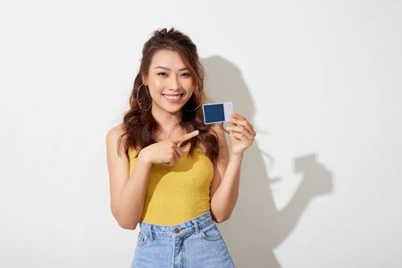 Photo of young smiling asian woman holding cardの写真素材