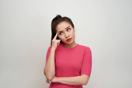 Portrait of thinking woman holding fingers on temples looking up having frustrated look trying to remember something important.の写真素材