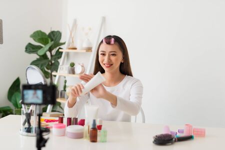 Young woman professional beauty vlogger or blogger recording cosmetic makeup tutorial with camera to share on social mediaの写真素材