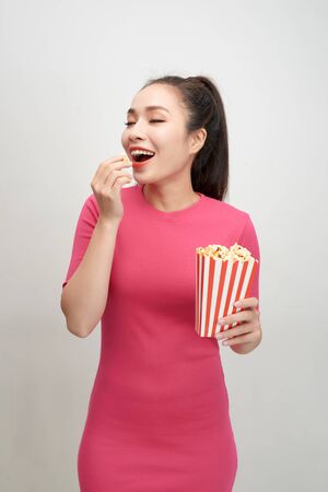 Portrait of a cheery pretty girl eating popcorn isolated over white backgroundの写真素材
