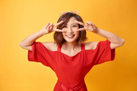 Portrait of funny emotional girl on yellow backgroundの写真素材