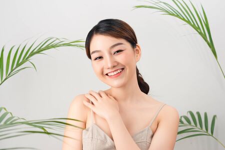 Portrait of Asian happy woman standing with green leaves around her on white backgroundの写真素材