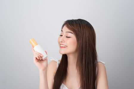 Asian woman showing cream on her hand, isolated on whiteの写真素材