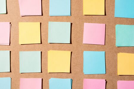 Multi colored notepads laying on a wooden plank board surfaceの写真素材